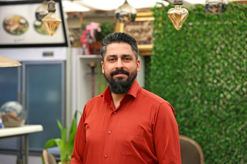 A restaurant owner in a red shirt standing in his restaurant