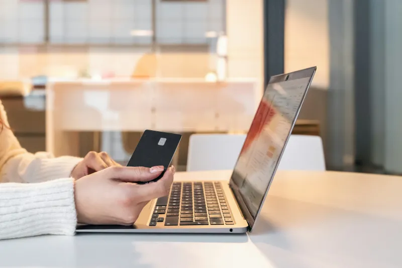 A shopper holding a card while paying on a laptop
