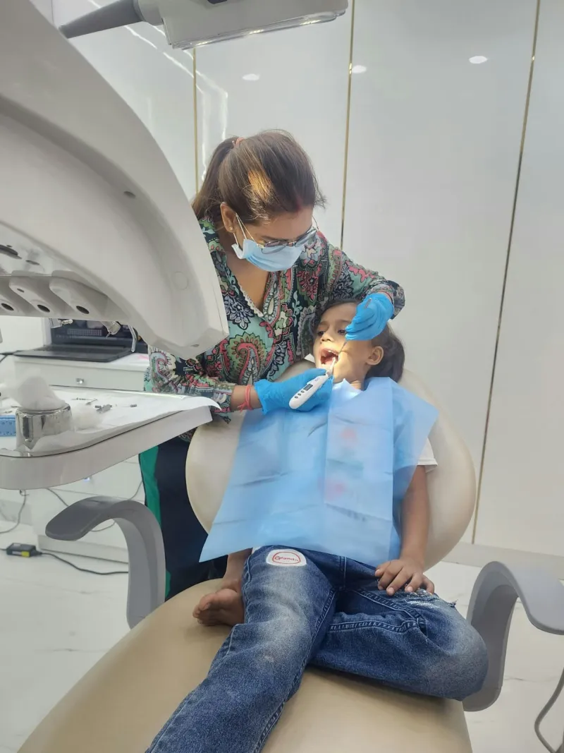 A dentist gently examining a young patient in the dental chair