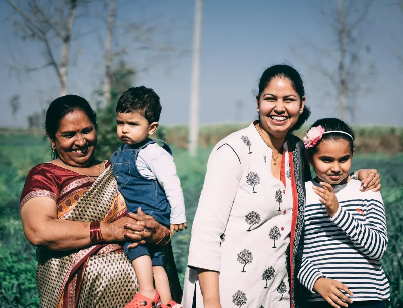 Three generations of a family smiling together in a green field