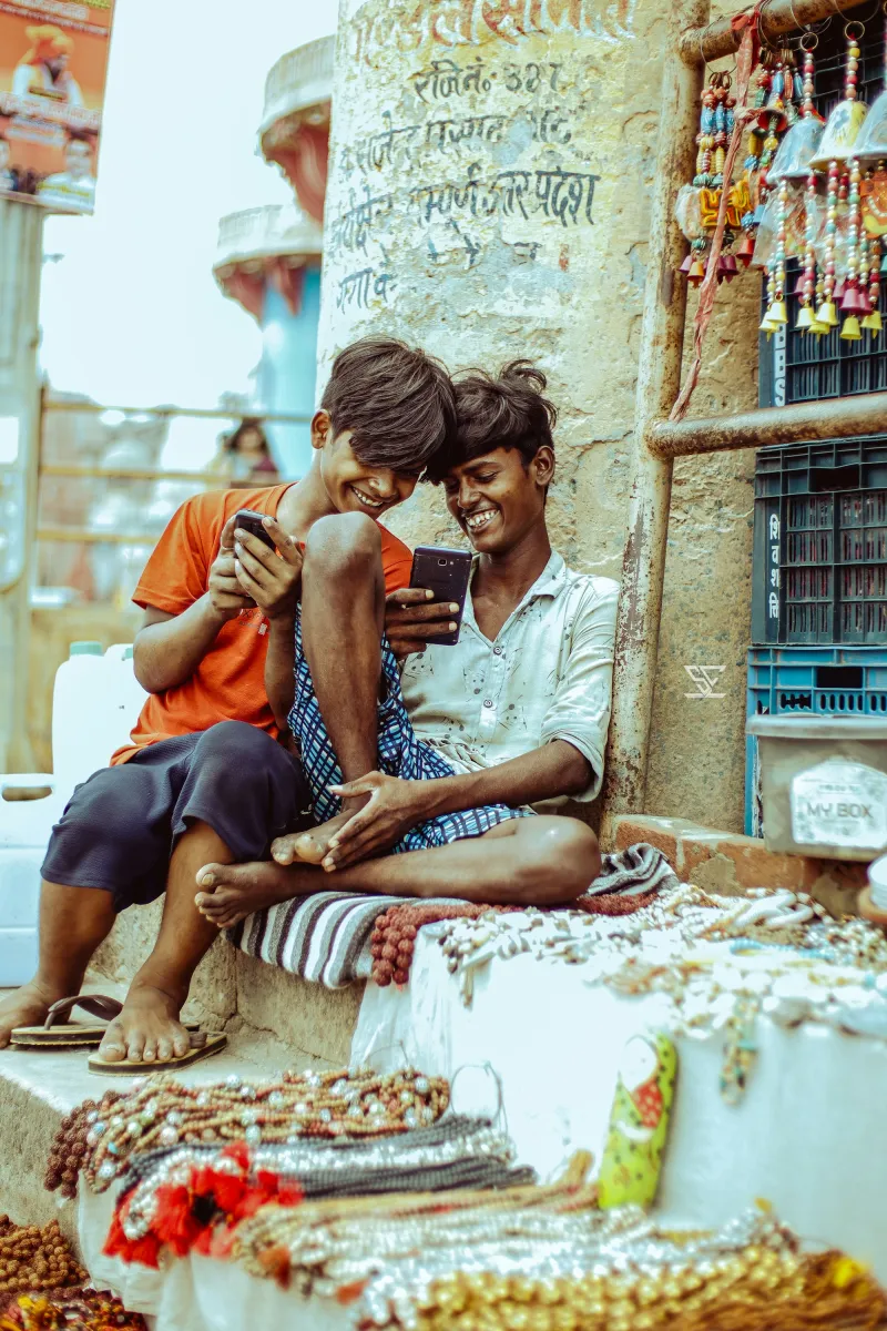 Two young friends laughing as they look at a phone together