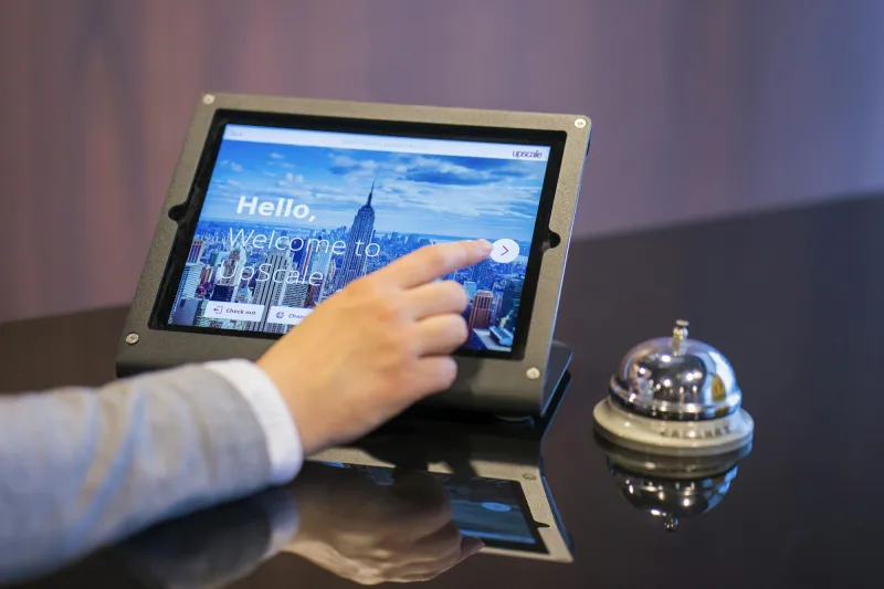 A guest checking in on a reception tablet beside a service bell