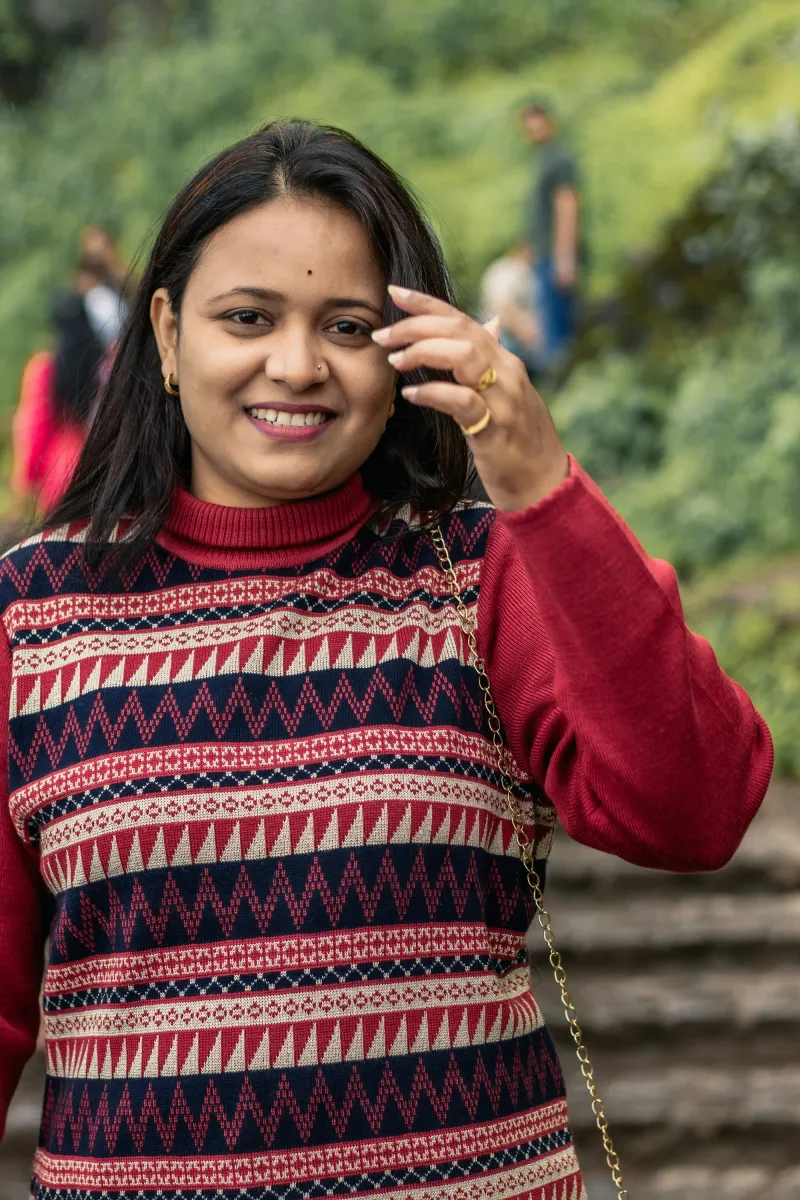 A woman in a red patterned sweater laughing as she looks at the camera