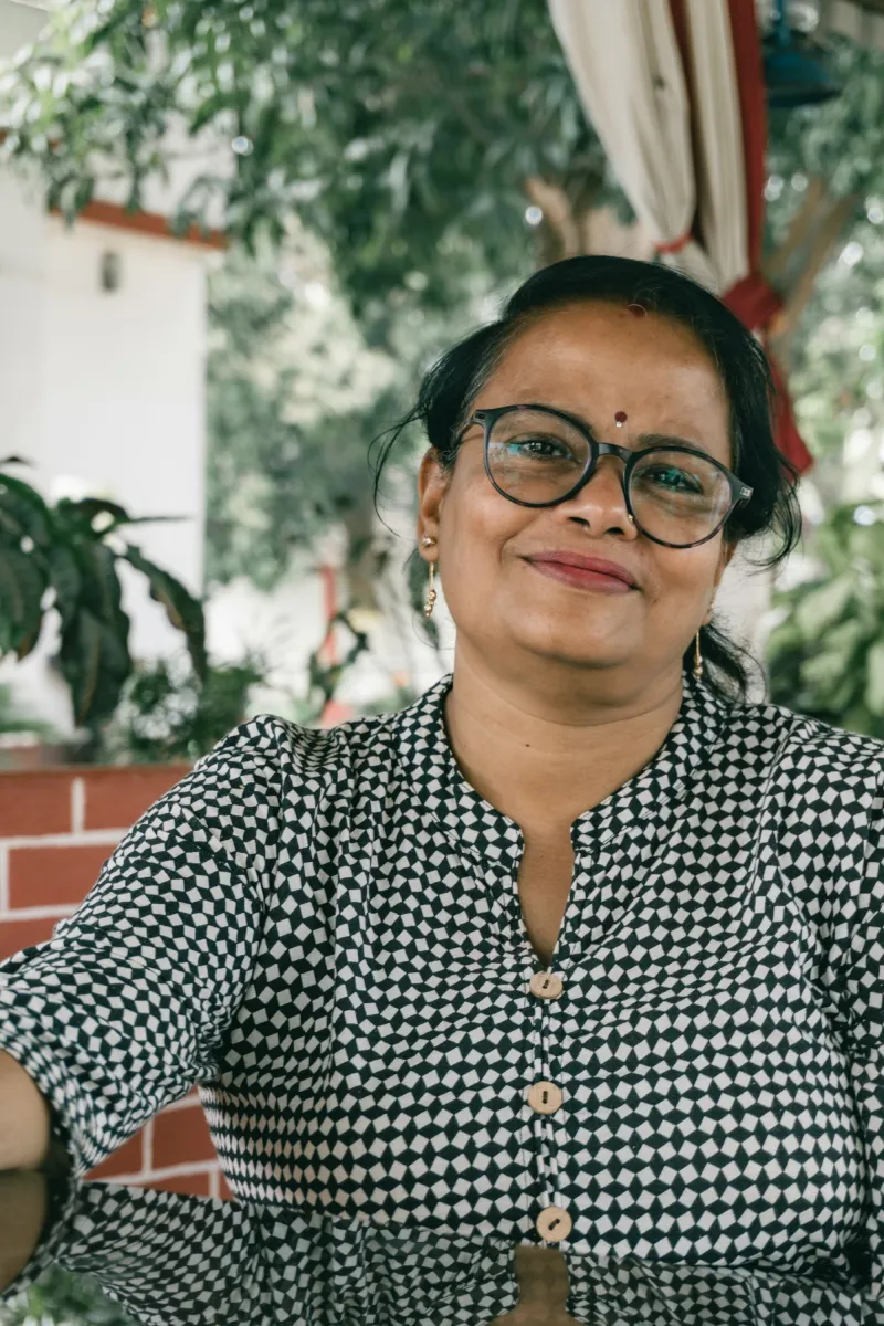 A smiling woman in glasses and a checked top