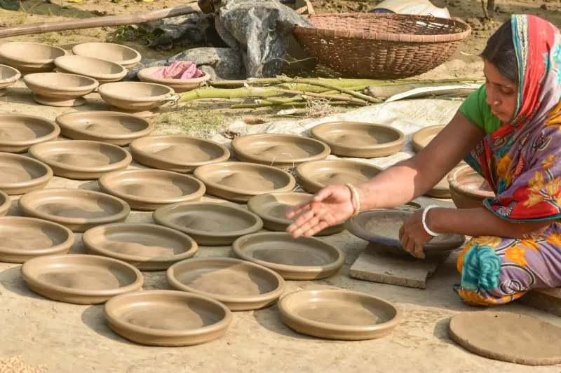 An artisan laying out rows of handmade clay plates to dry